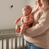 Een moeder houdt haar baby vast naast het babybed